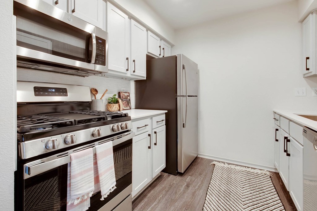 a kitchen with stainless steel appliances and white cabinets a kitchen with stainless steel appliances and white cabinets at The Olivine, Austin, 78727